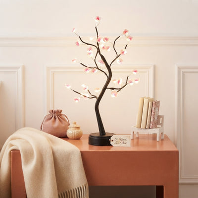 LED Cherry Blossom Bonsai Lamp glowing on a terracotta table with warm cream and rose colored decor.
